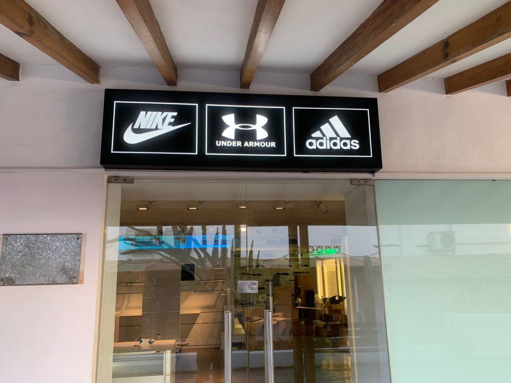 Caja de luz con marcas deportivas en entrada de tienda